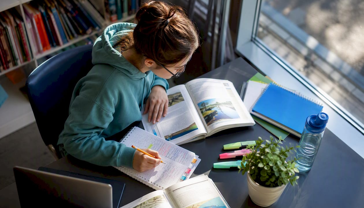 Student studying IB ESS materials at desk