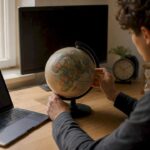 Hands rotating globe on study desk