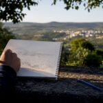 Student drawing a landscape field sketch outdoors