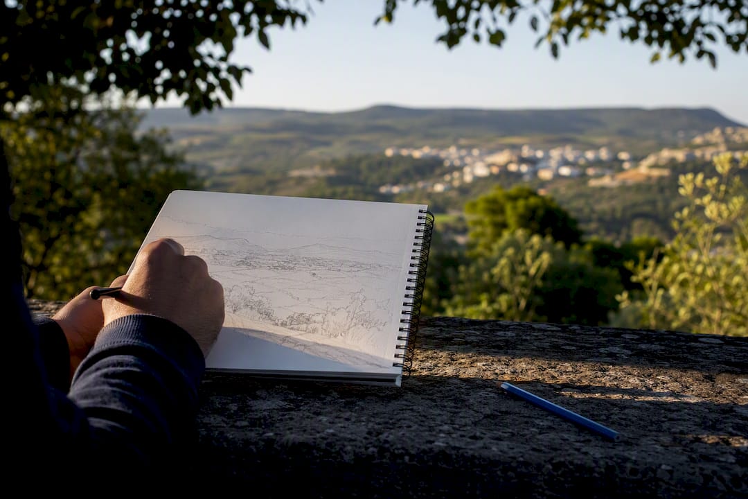 Student drawing a landscape field sketch outdoors