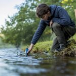Student measuring river velocity with flow meter